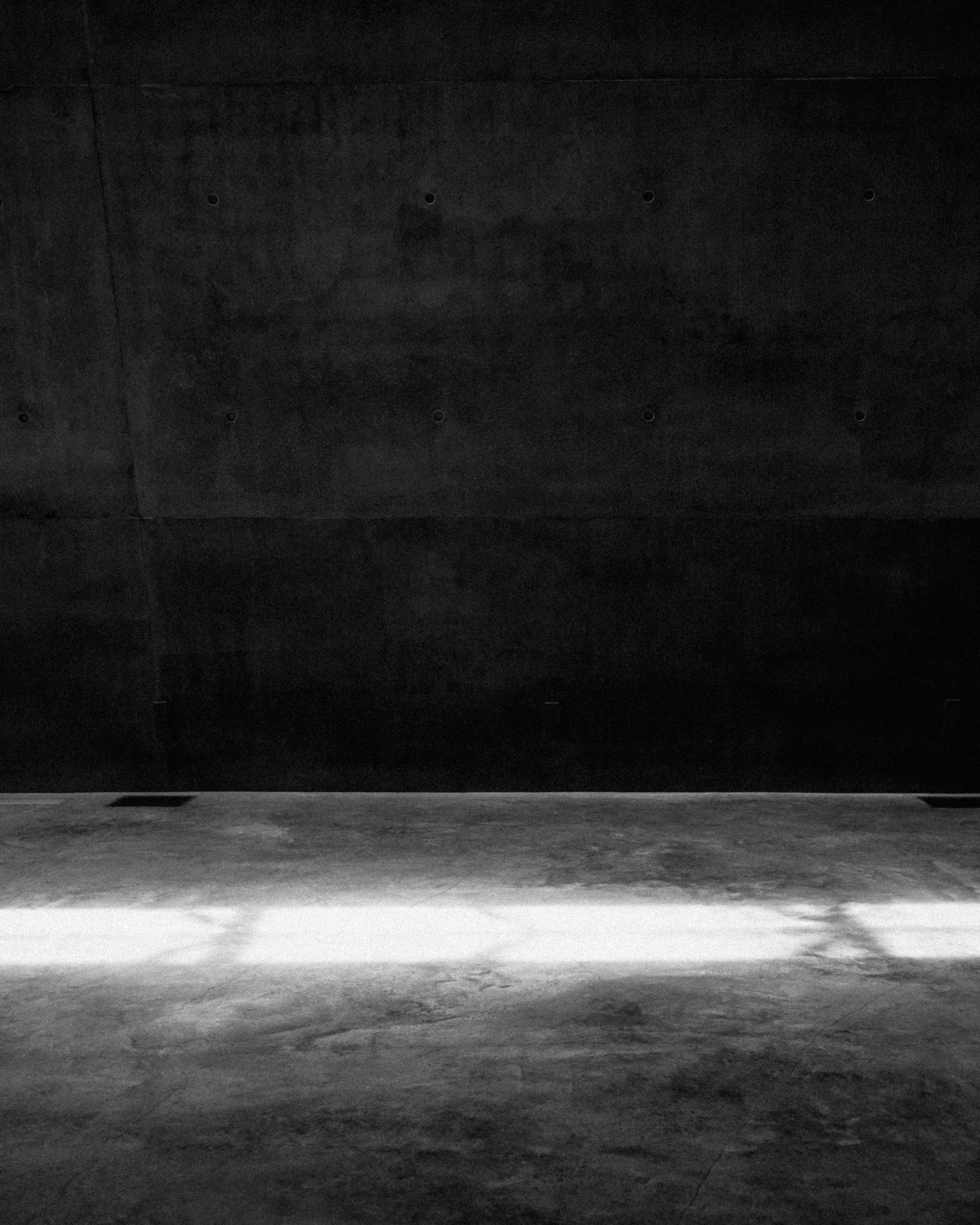 A single beam of light cutting across a dark concrete space.